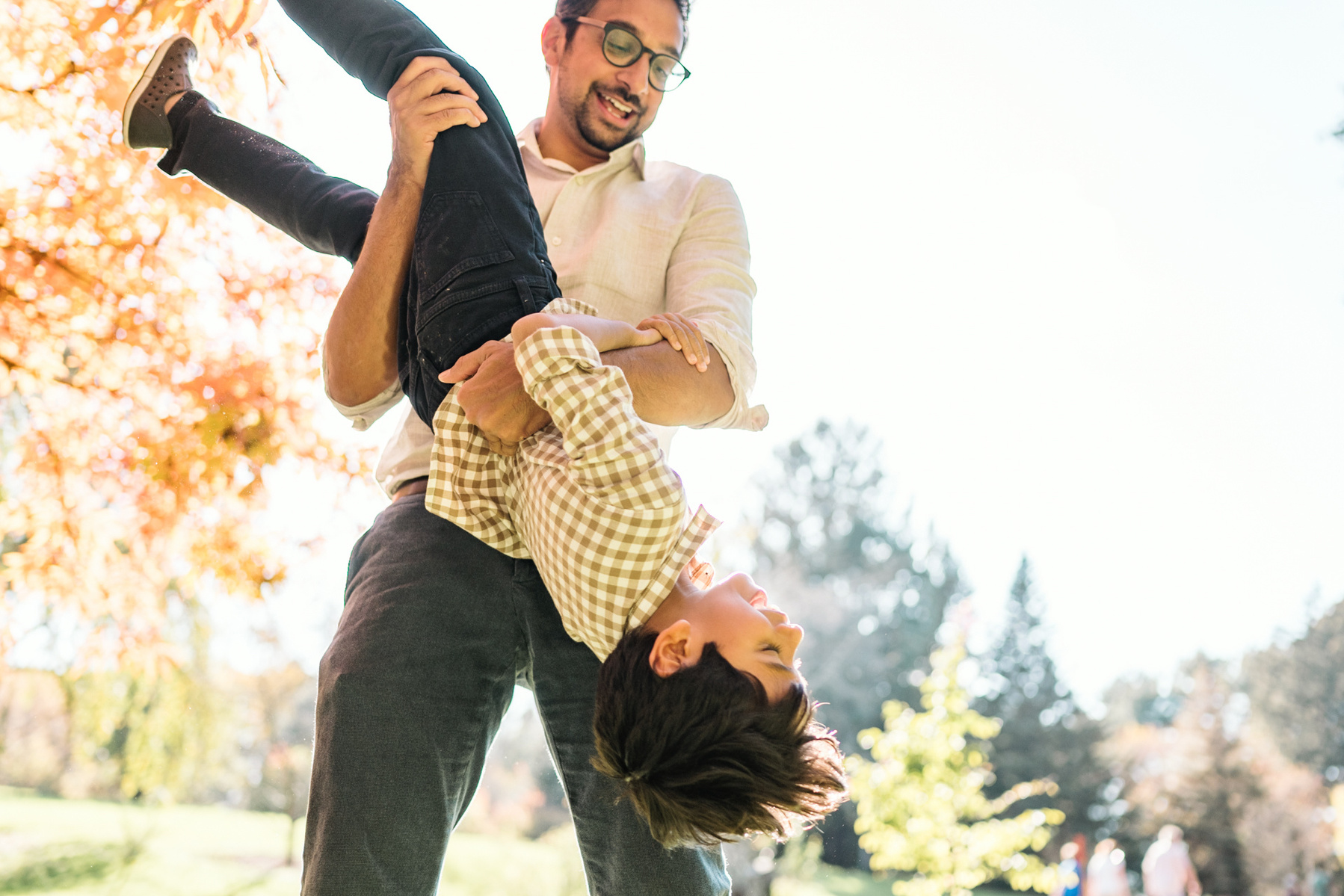 A boy is flipped upside down in the arnold arboretum during their boston family photography session by west roxbury family photographer korri leigh crowley