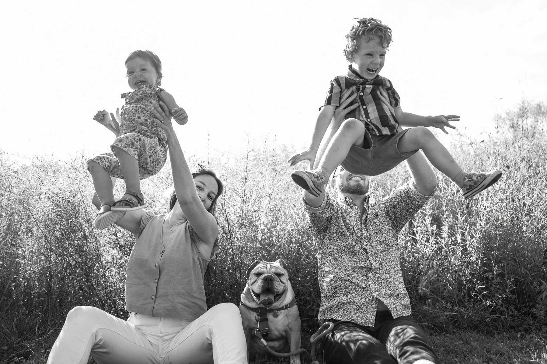 Parents throw their young children in the air at a family photo session at Fisher Hill Reservoir Park in Chestnut Hill by Brookline family photographer Korri Leigh Photography