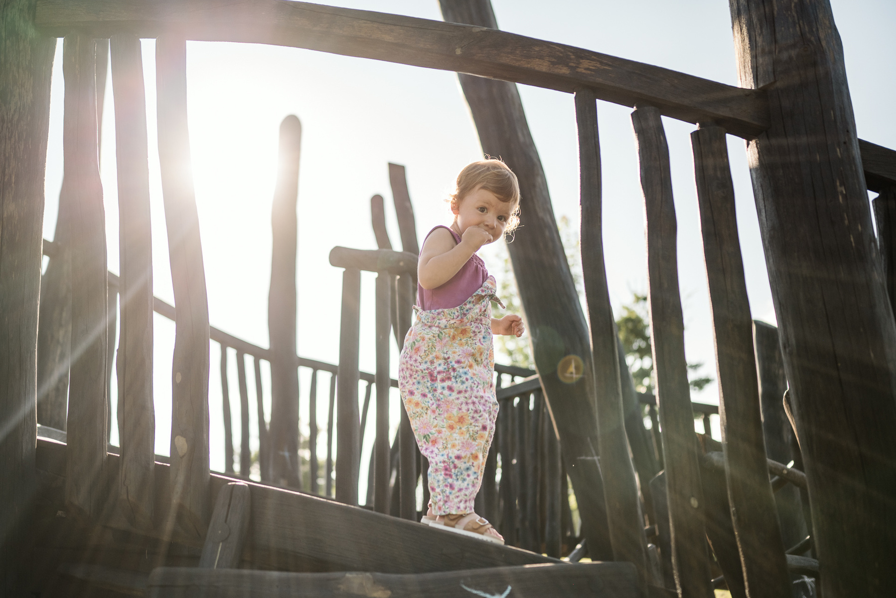 A young girl plays on a structure at Fisher Hill Reservoir Park in Chestnut Hill by Brookline family photographer Korri Leigh Photography