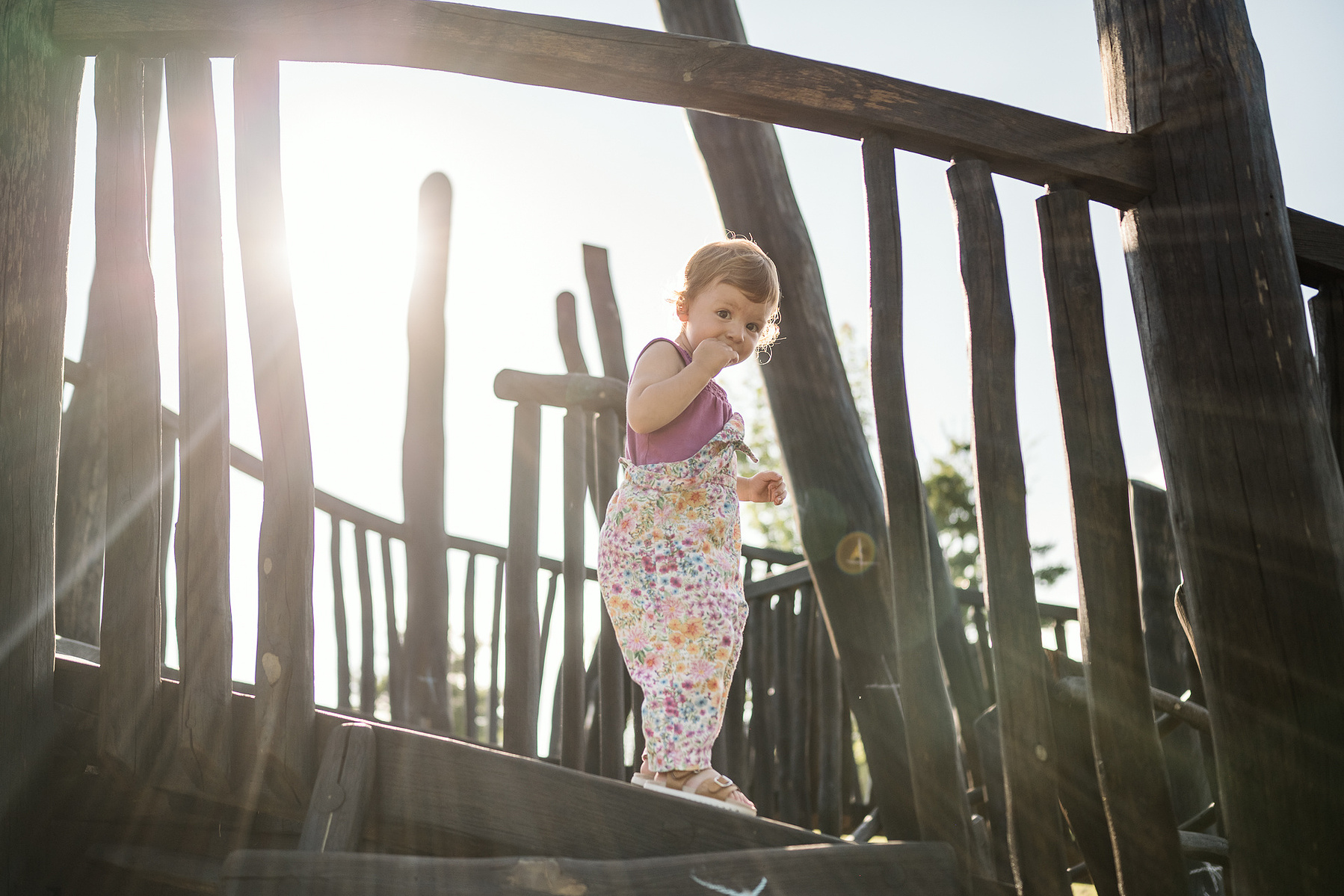 A young girl plays on a structure at Fisher Hill Reservoir Park in Chestnut Hill by Brookline family photographer Korri Leigh Photography