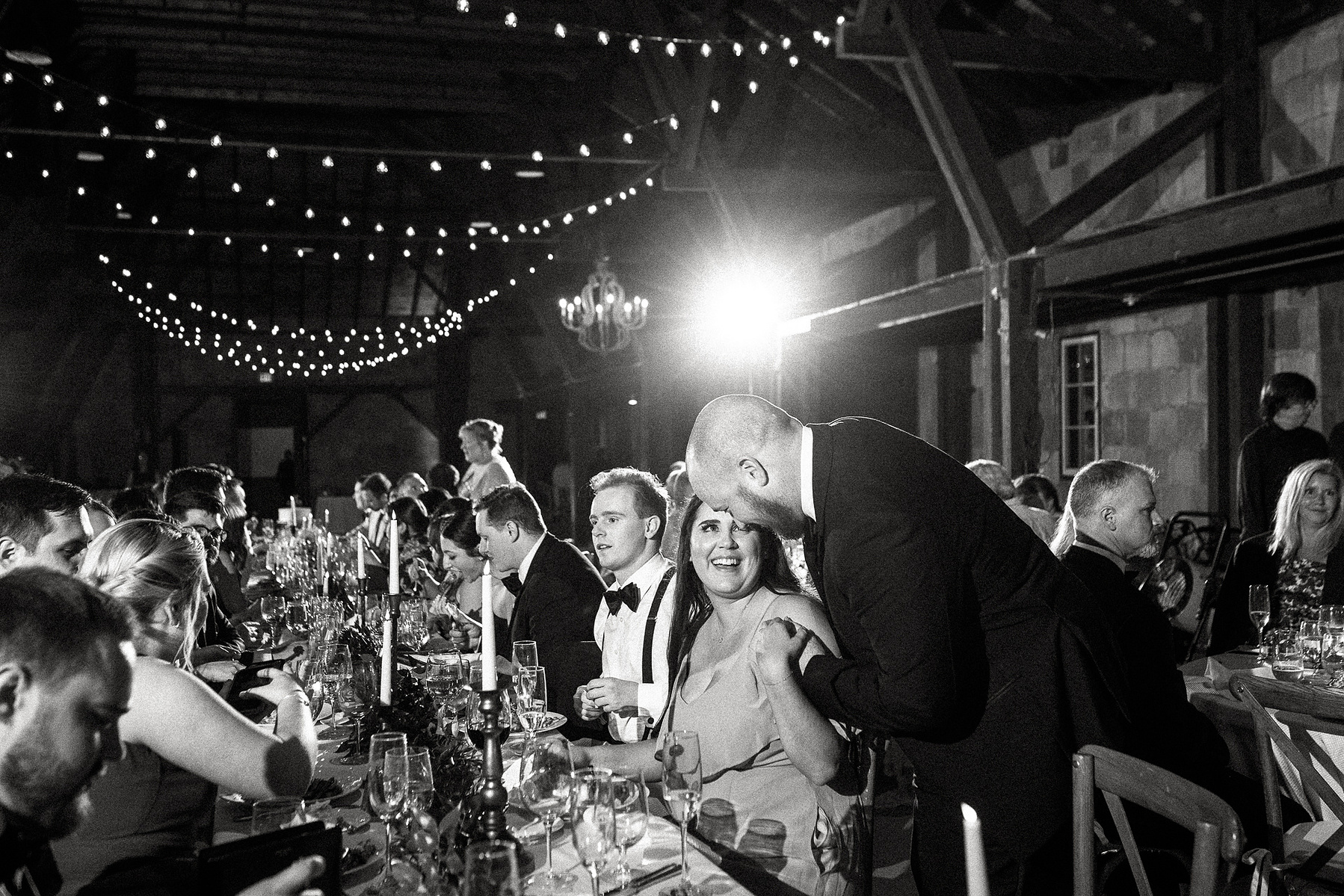 Guests smile and hug during dinner at a Barn at Castle Hill wedding