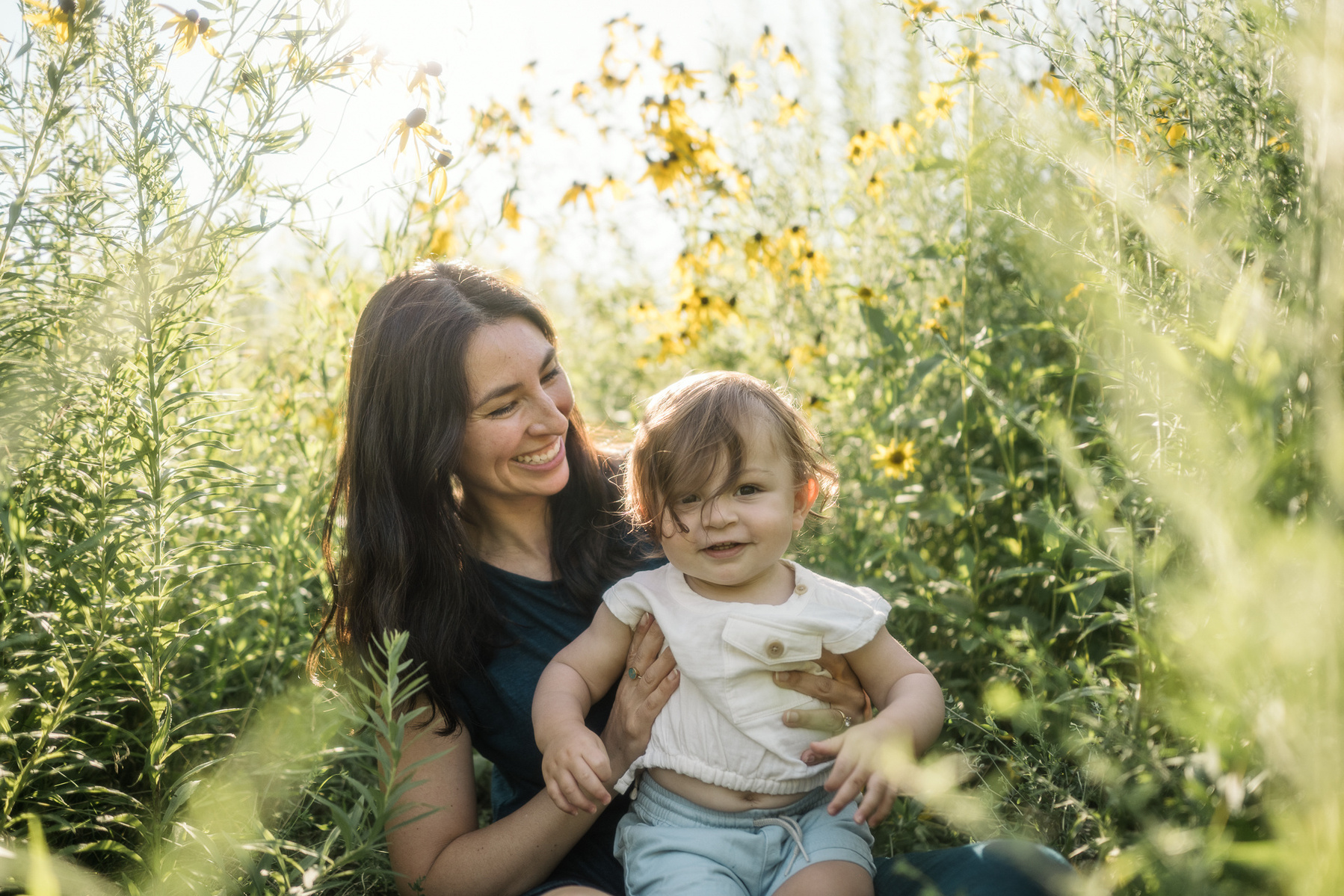 A mother looks at her baby son in the sunshine at Fisher Hill Reservoir Park in Brookline MA