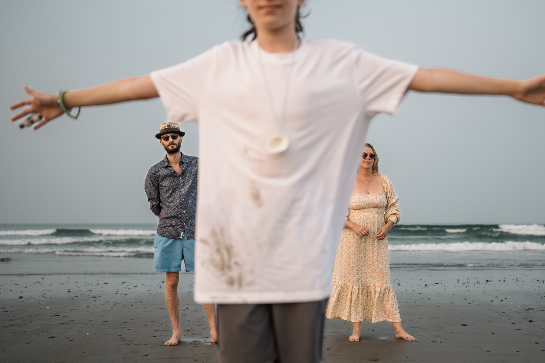 A family poses with the son in foreground and parents in background on Nantasket Beach at their Hull family photography session by Korri Leigh Photography