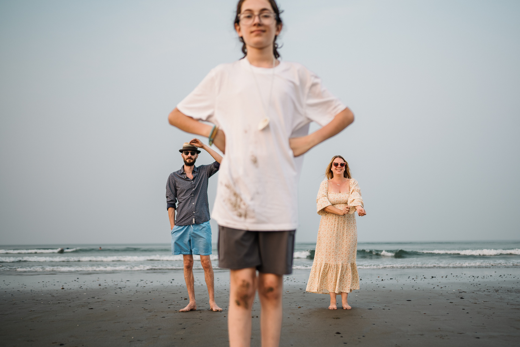 A family poses with the son in foreground and parents in background on Nantasket Beach at their Hull family photography session by Korri Leigh Photography