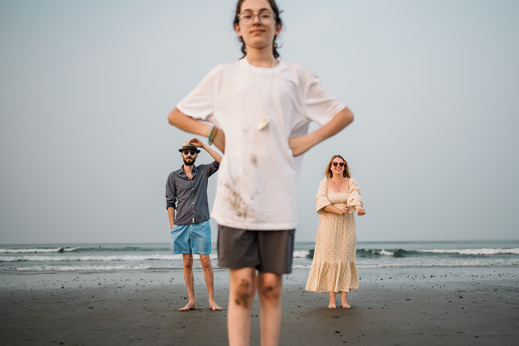 A family poses with the son in foreground and parents in background on Nantasket Beach at their Hull family photography session by Korri Leigh Photography