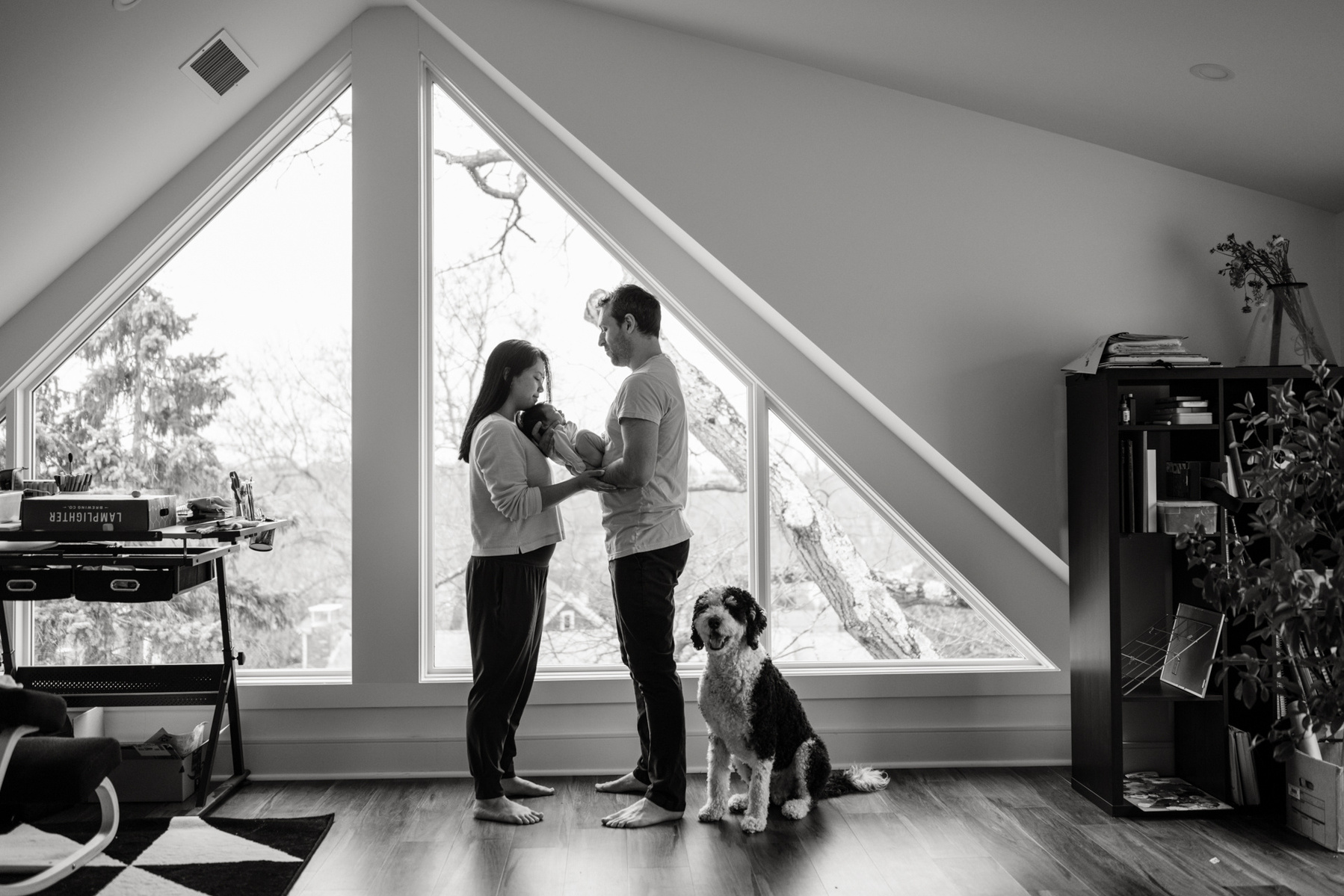 Mom and Dad holding their daughter  in silhouette during an arlington ma newborn photography session