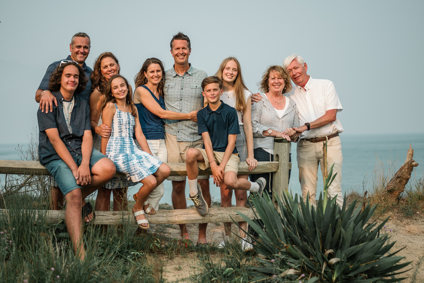 An extended family of 10 members pose and smile for the camera at Nauset Lighthouse in Eastham Massachusetts