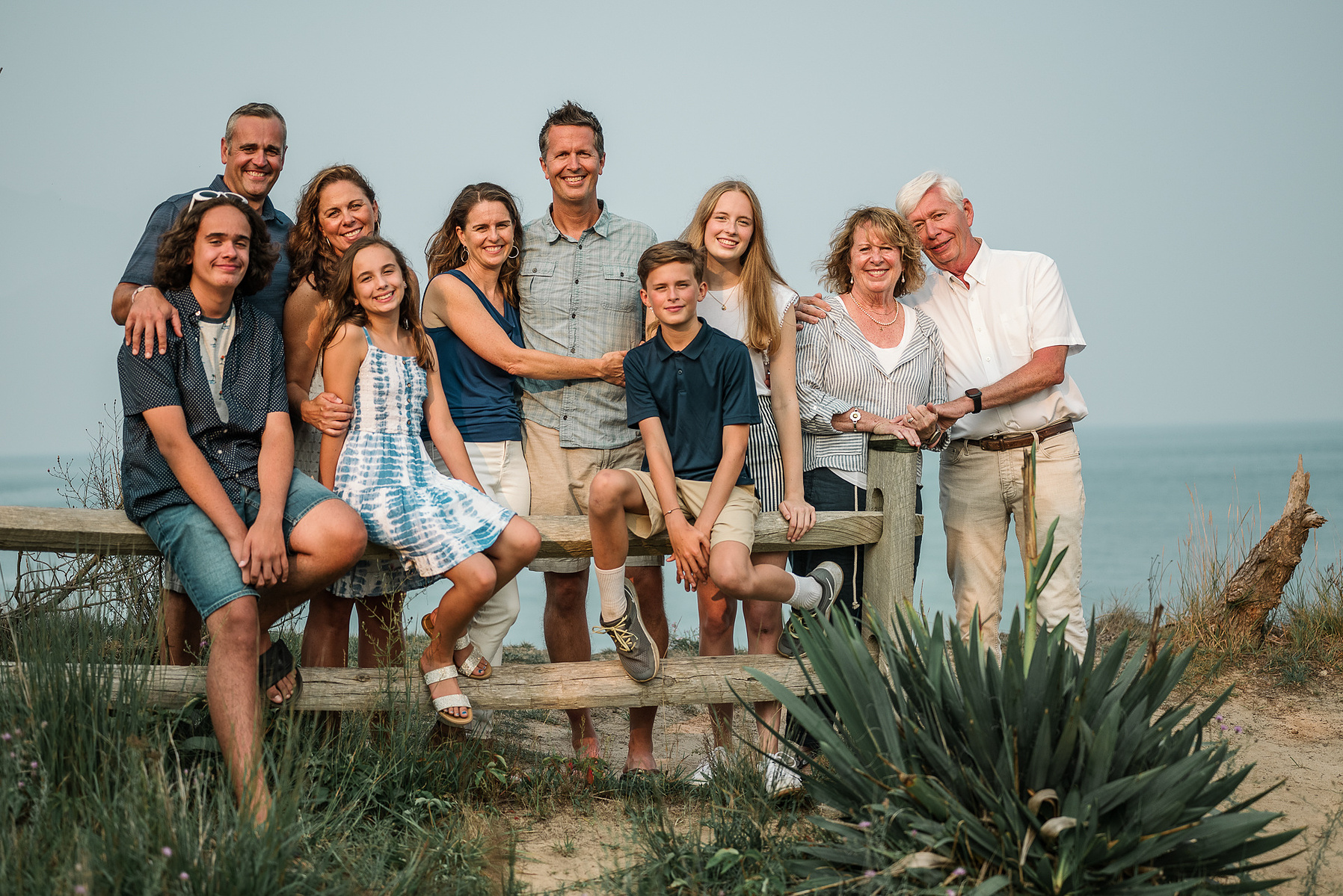 An extended family of 10 members pose and smile for the camera at Nauset Lighthouse in Eastham Massachusetts