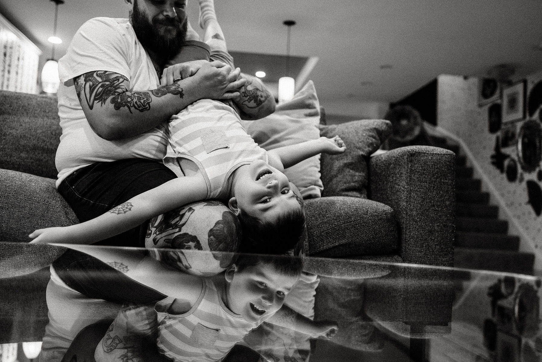 A young boy is mirrored in a glass table during a boston documentary family photo session