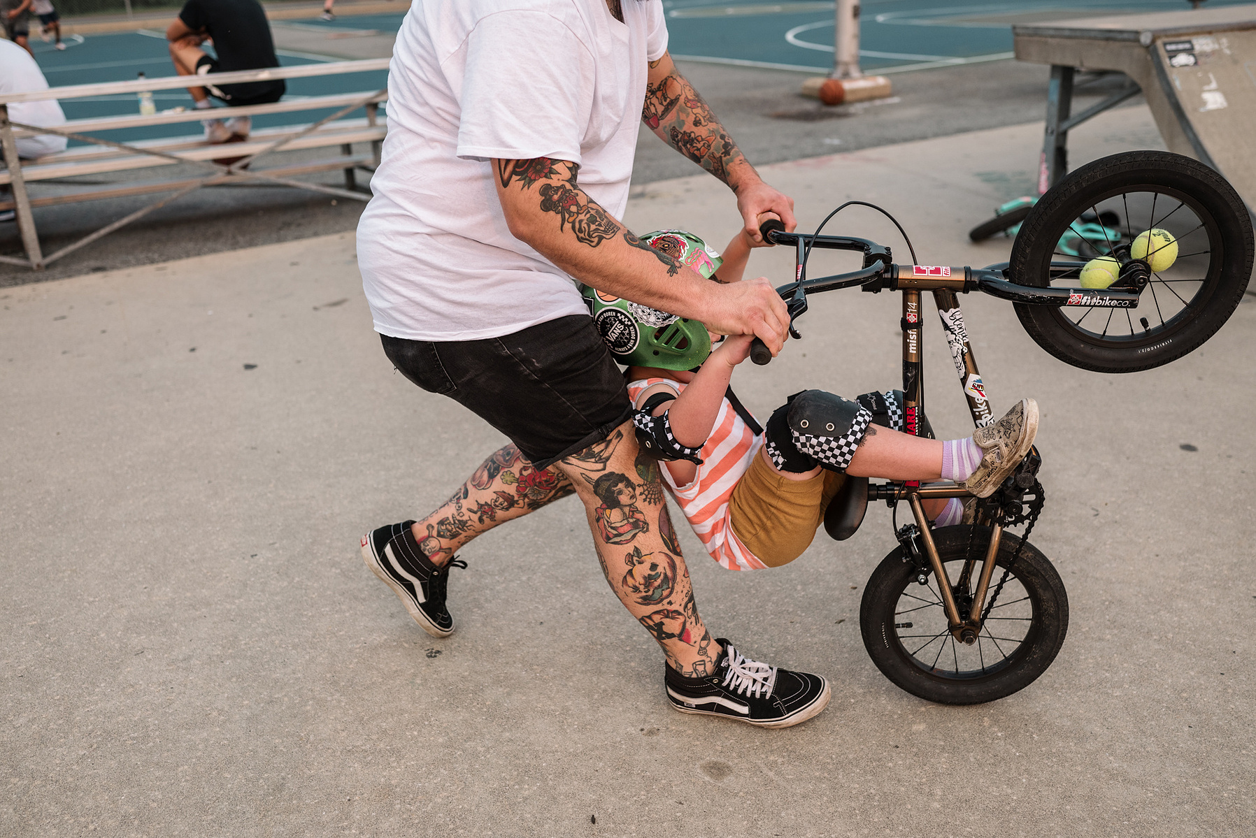 A young boy rides a bmx bike with his tattooed dad during a family photo shoot at Innocenti skatepark in Beverly MA