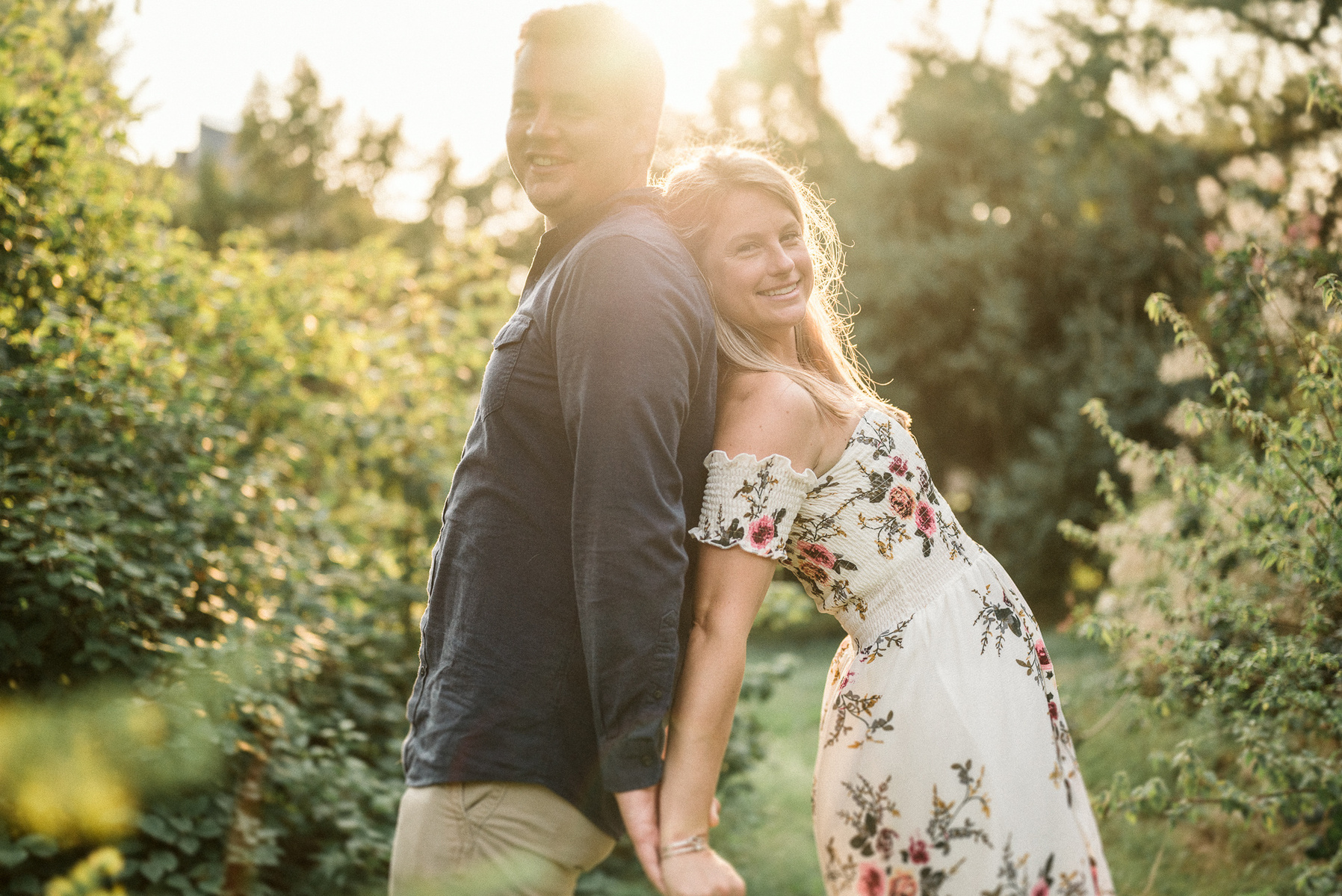 a couple leans on each other in the sunshine during their arnold arboretum engagement session