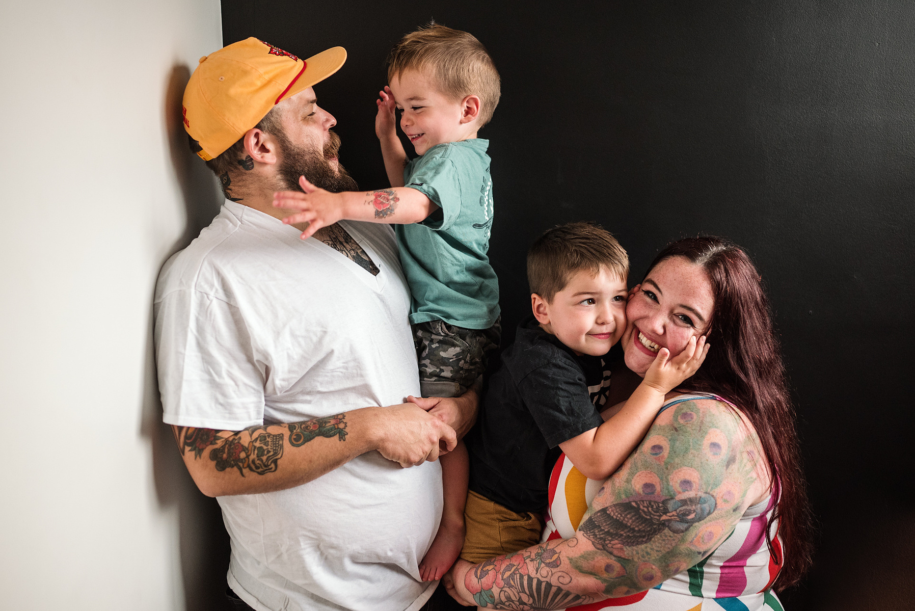 A tattooed family laughs and hugs during their boston in home family photography session