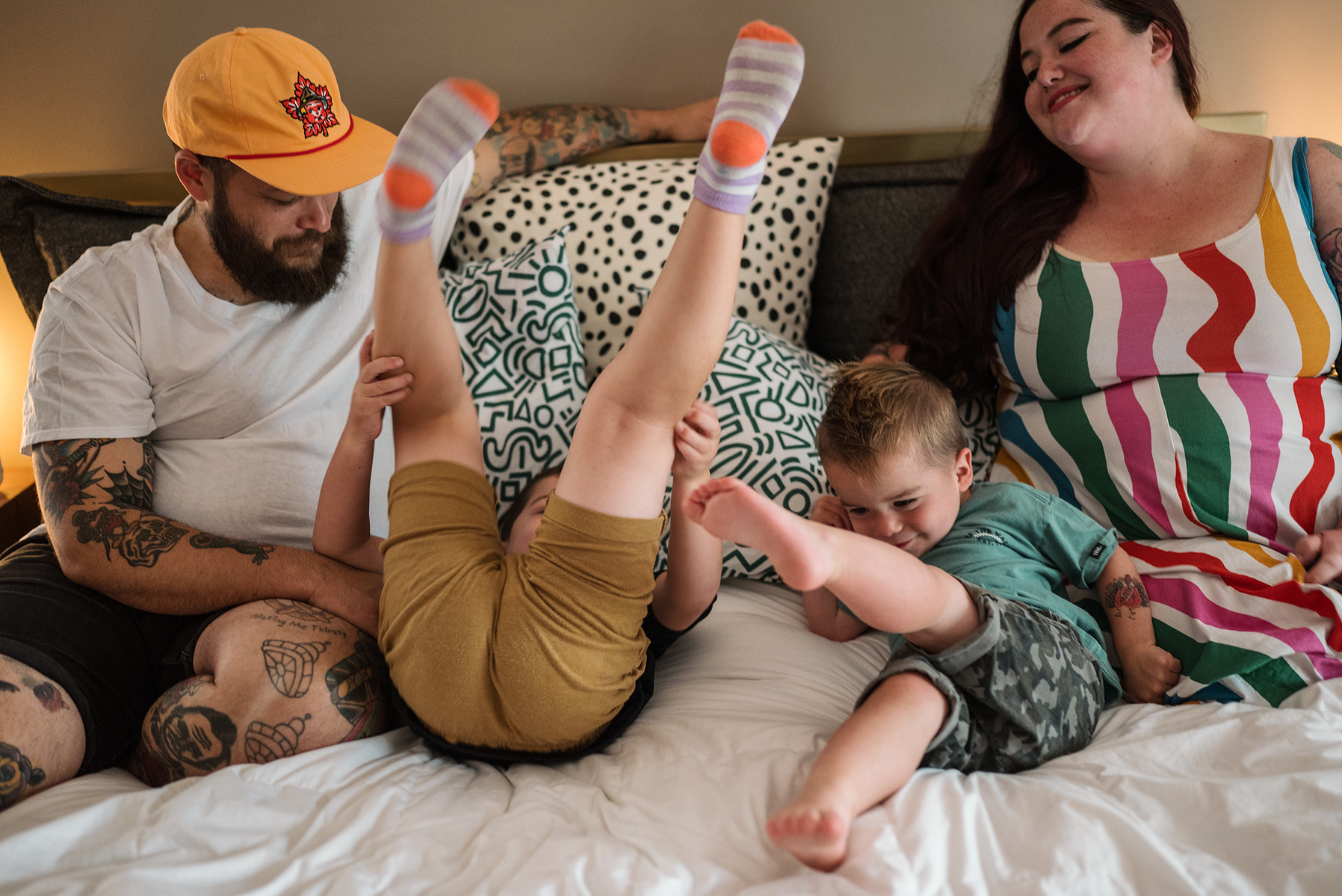 A family laughs and cuddles on a bed during their in home family photography session in Salem, MA