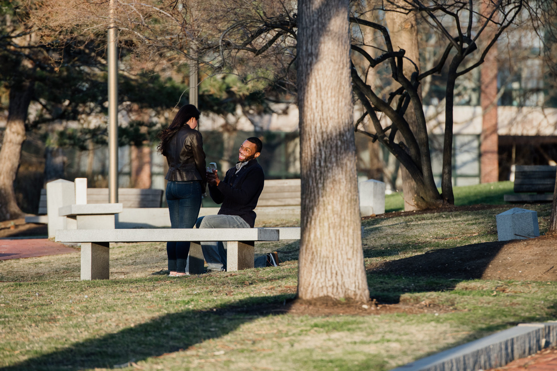 A man on one knee proposes to a woman in the Charlestown Navy yard 