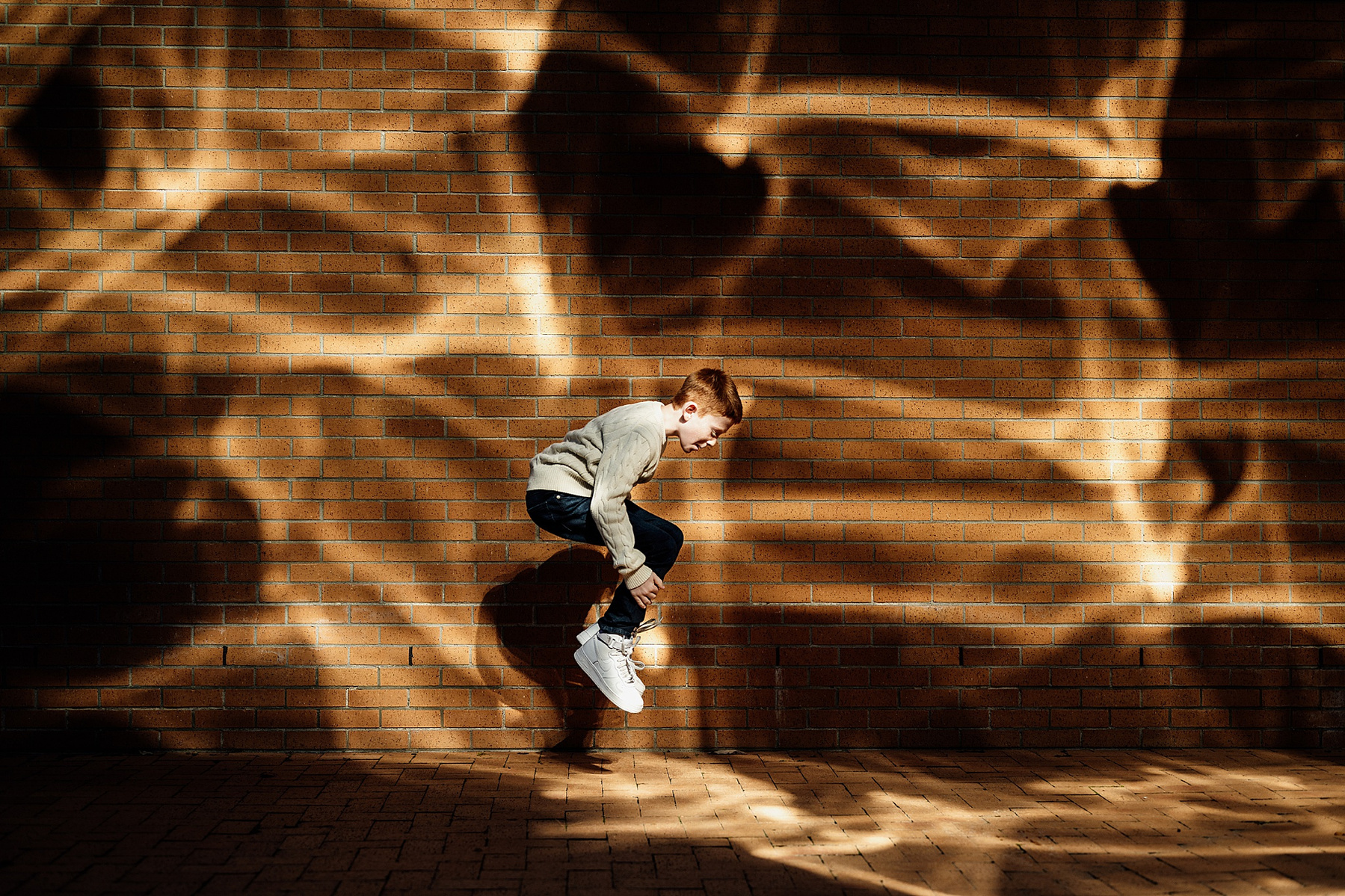 a child jumping in front of a patterned wall on the MIT campus by boston family photographer korri leigh photography