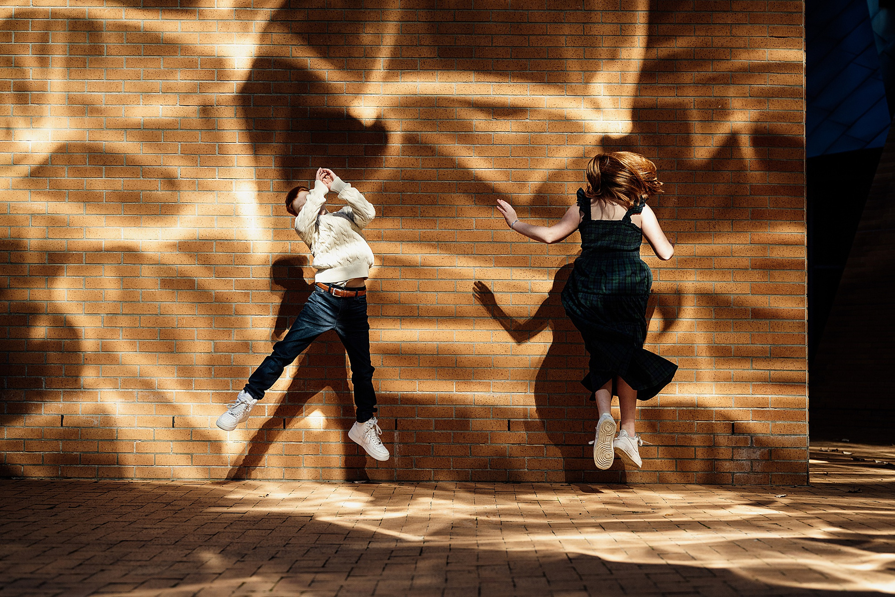 children jumping in front of a patterned wall on the MIT campus by boston family photographer korri leigh photography