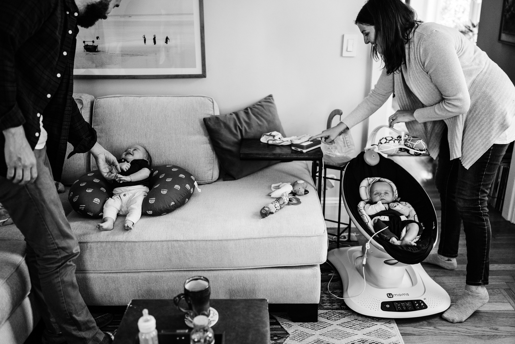 Parents care for newborn twins reclining on a couch