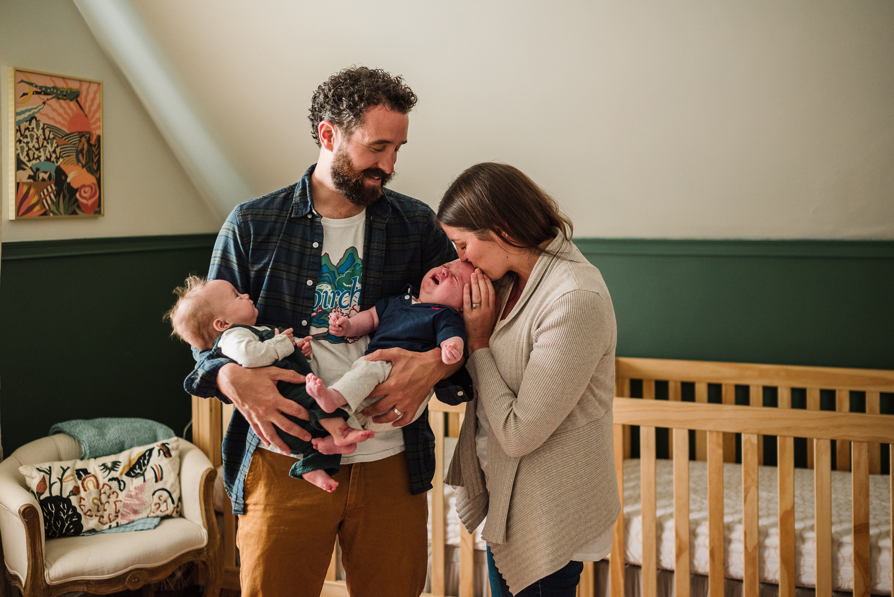 A mother kisses the heads of her newborn twins held by their father 