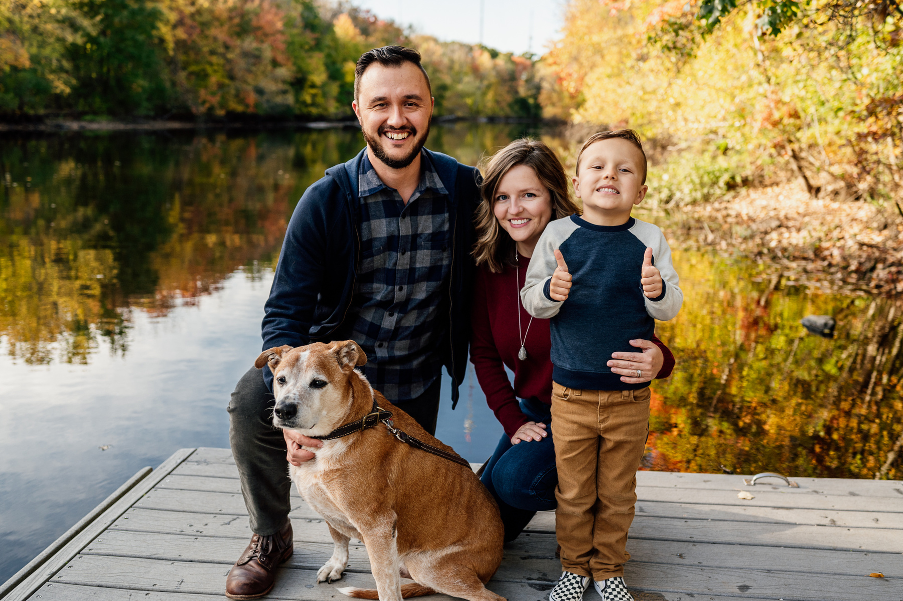 A family hugs and smiles with their dog during their fall mini-session in Boston by West Roxbury family photographer Korri Leigh Photography