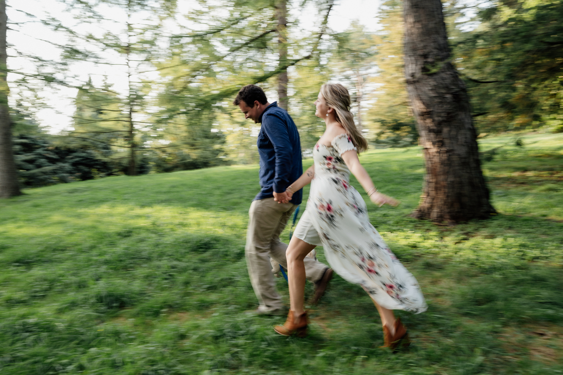 a couple holds hands and runs during their arnold arboretum engagement session
