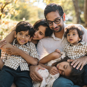 An indian american family sits, smiles and cuddles together during their boston family photography session in the arnold arboretum