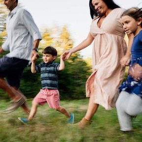 A family of 4 joyfully runs past the camera in a blur