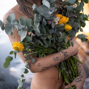 Nude woman holding a bouquet of flowers outdoors in Stockholm, Sweden.