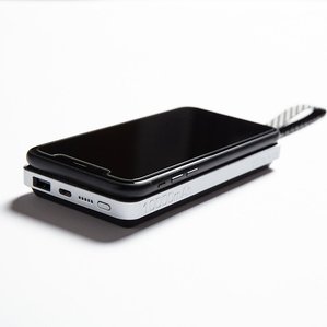 black smartphone sitting on portable charger brick on white backround