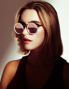 Chloe Holmes woman model headshot profile with blonde hair and fair skin wearing circular mirrored sunglasses with half of face illuminated by light and other half covered in dark shadows in front of white background photographed by william gormley