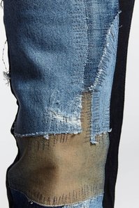 close up of blue denim patch stitched on black denim pants
