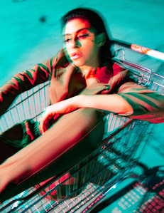 moody colorful portrait of close up of vartuhi oganesyan woman model sitting in shopping cart looking to her right  styled in business suit illuminated by red flash blue ambient light background motion movement blurred effect photograph by william gormley