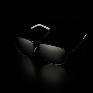 black metal rimmed mirrored lens sunglasses sitting on a black surface with a dark background in soft light