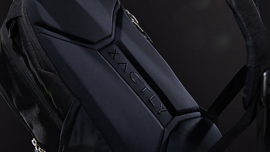 Dark grey and blue backpack with side pockets and straps and metal zippers floating in black dark space with soft light