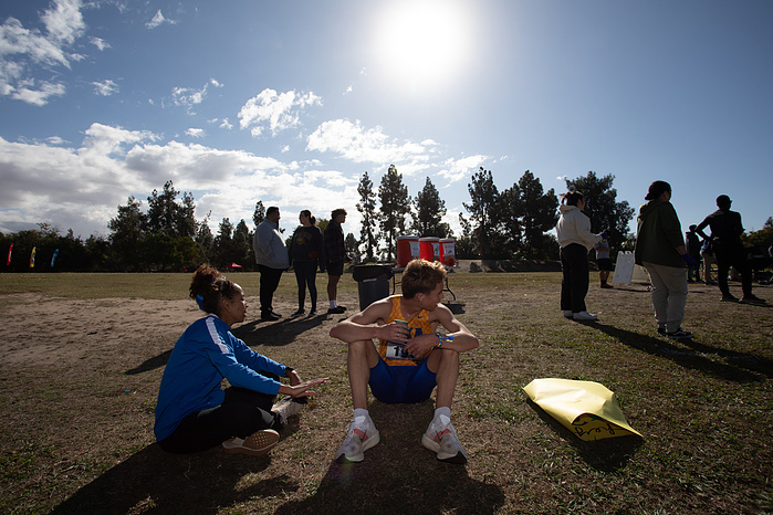 Naylah Santos sits with Andre as he catches his breath watching the rest of his team cross the finish line at CalPac.