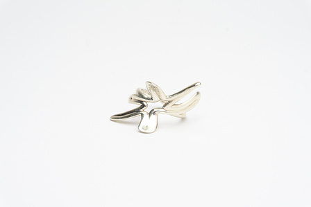 A minimal silver ring is pictured in top view on a neutral white ground. It features a stylized flower or star form that is warped and following the curve of the ring band.