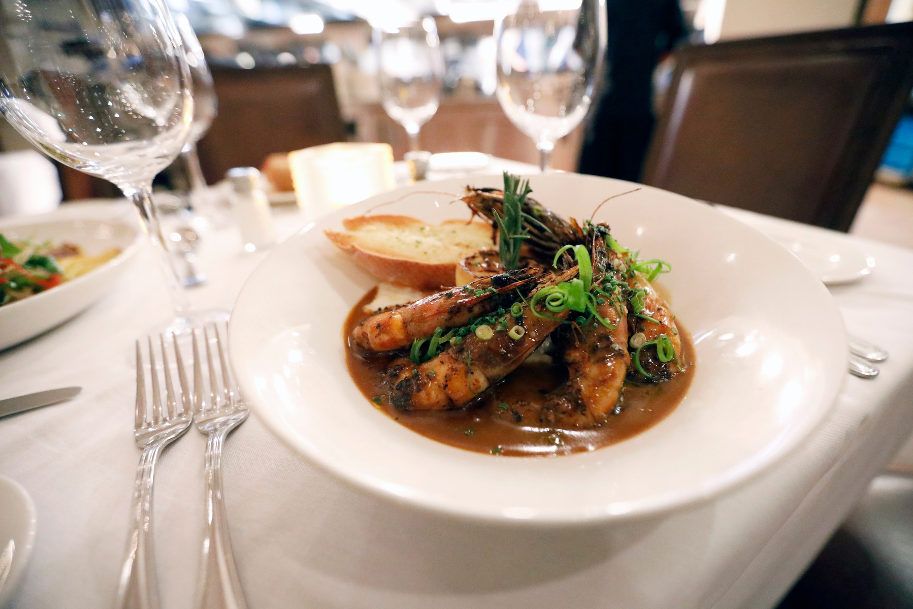 A plate of their signature jumbo Gulf shrimp, New Orleans BBQ sauce, Abita beer, stone-ground grits with a side of French bread sits on the table at Tableau, a top Cajun & Creole restaurant nestled in the French Quarter of New Orleans, on Tuesday, Aug. 8,