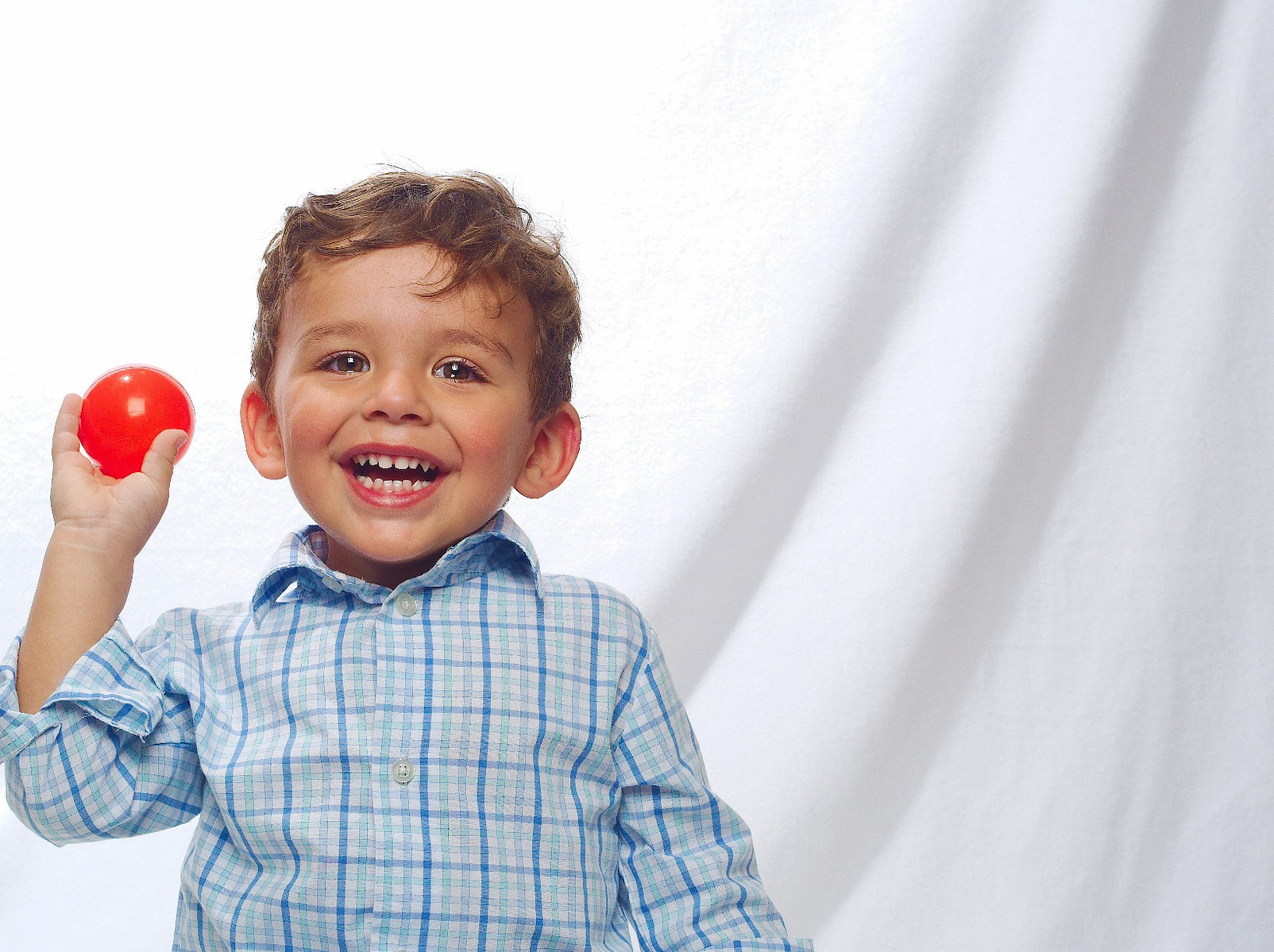 Image Description: "A toddler throwing a ball during a high key photo session."