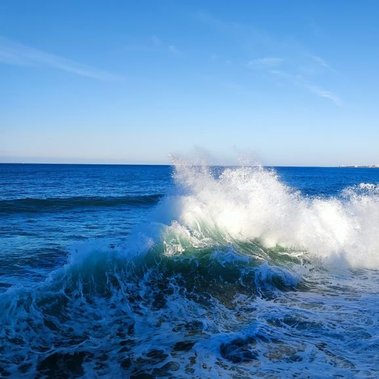 L'océan est agité et les vagues entrantes choquent les vagues partantes dans un ressac spectaculaire. le soleil illumine l'écume dans un bleu immaculé