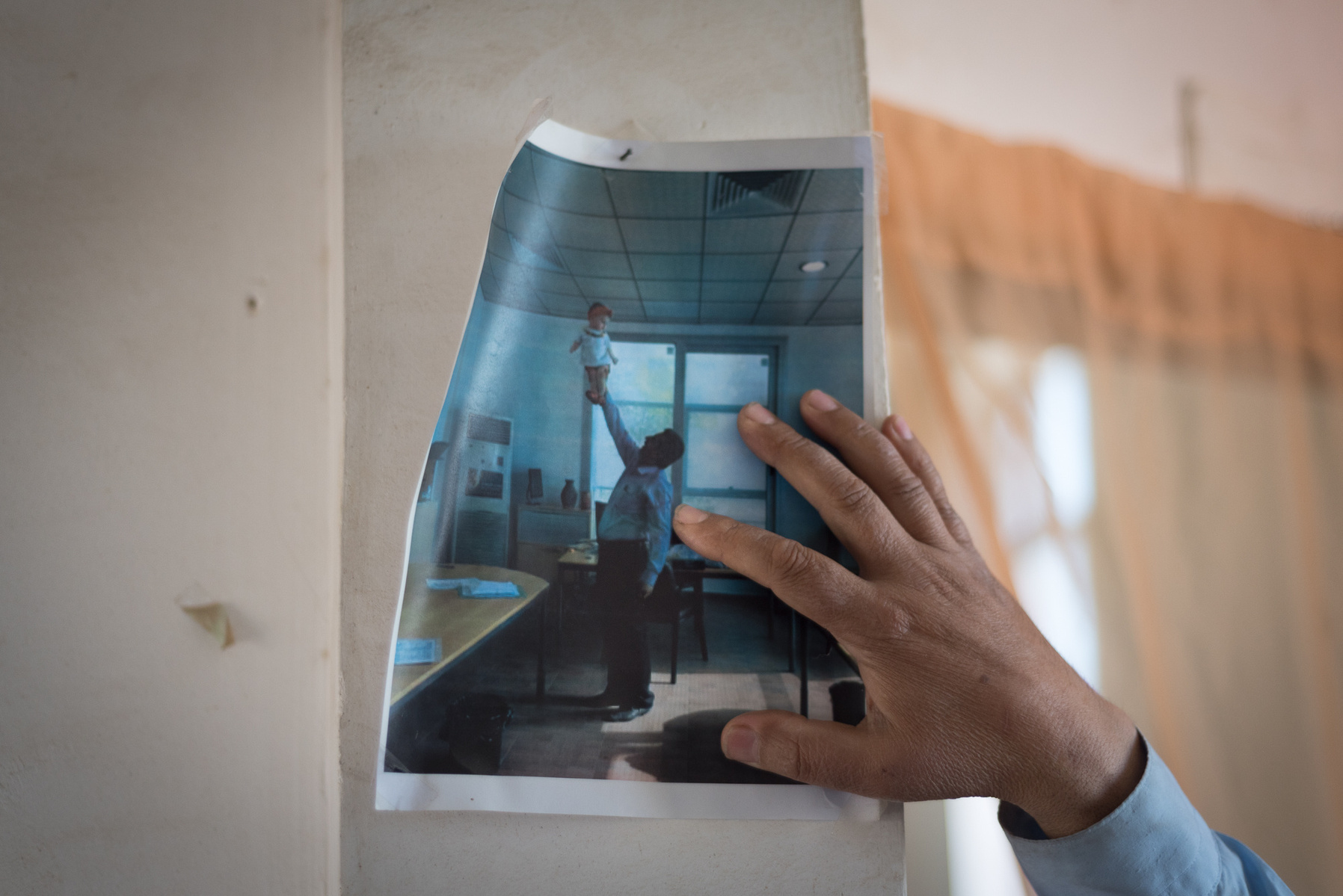 Halabja, KRI. A photo of Aras Abid Akram, a survivor and deputy director of Halabja chemical victims society, holding a child is hung in his office at Save the Children KRG. Akram lost 26 family members in the chemical attack that hit Halabja on March 16t