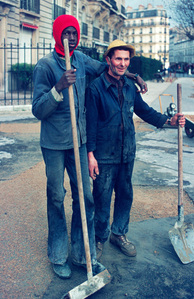 "Street portrait of two workers repairing the street, showcasing their teamwork and dedication amidst the urban environment."