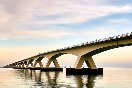 View of the Zeeland Bridge stretching across the Oosterschelde, with its rhythmic concrete arches and long spans connecting the islands of Schouwen-Duiveland and Noord-Beveland under a wide Dutch sky.
