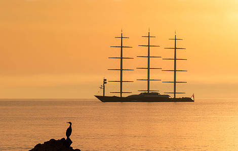 Maltese Falcon yacht at anchor near L&amp;amp;amp;#x27;Escala during sunrise, with soft light and still waters.
