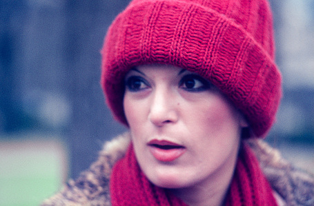 Street portrait of a young woman wearing a red woolly hat and scarf.