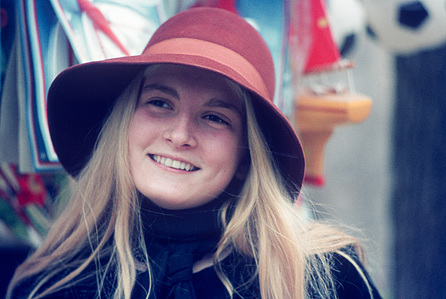 Street portrait of a Parisienne with blonde hair wearing a large red hat.