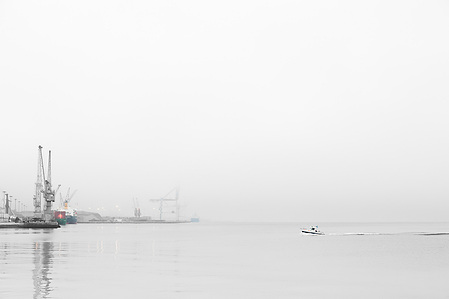 Pilot boat approaching the quay in the port of Setúbal at dawn to deliver a harbour pilot, with industrial port structures in the background.