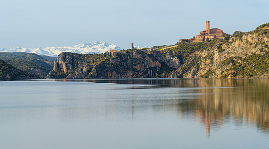 Torreciudad Sanctuary seen in a sweeping panoramic shot, its bold brick design rising from the rugged, serene landscape of northern Spain.