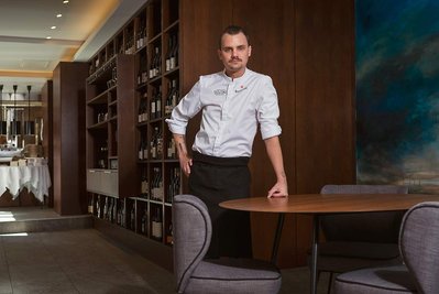 Portrait en situation de Balthazar Gonzalez, chef étoile du restaurant l'Hedone à Toulouse. Il est debout appuyé à une table.