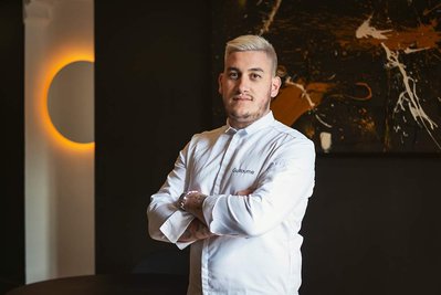 Portrait en situation de Guillaume Momboisse, chef étoile du restaurant le Sept à Toulouse. Il est debout les bras croisés.
