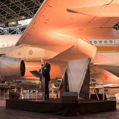 Dans le cadre d'un reportage événementiel de Johanna Senpau à Aéroscopia sur Toulouse, un dirigeant d'entreprise fait un discours sous l'aile d'un avion.