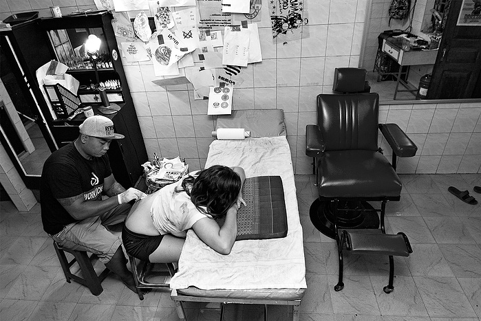 Black + White Fine Art Portrait of a young Cambodian man doing a tattoo on a females back in his tattoo parlour.
Fine Art Portrait
Black + White Photography
Fine Art Gallery
Artistic Photography
Ring Light Photography